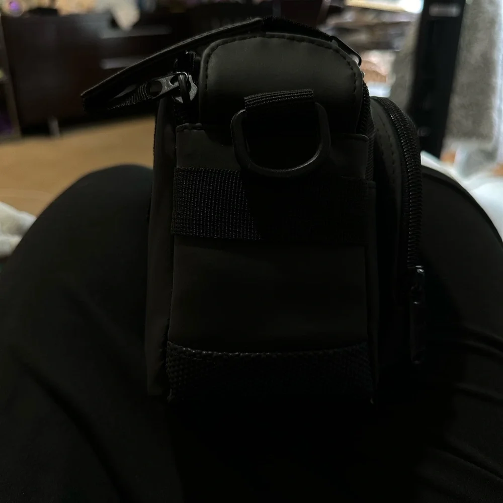 Canon black camera bag with zipper packets, and a handle at the top.